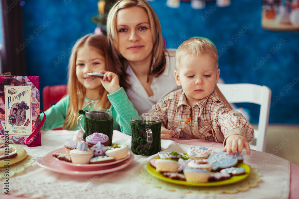 Children takes cookies from the plate while their mother stand o Children takes cookies from the plate while their mother stand o