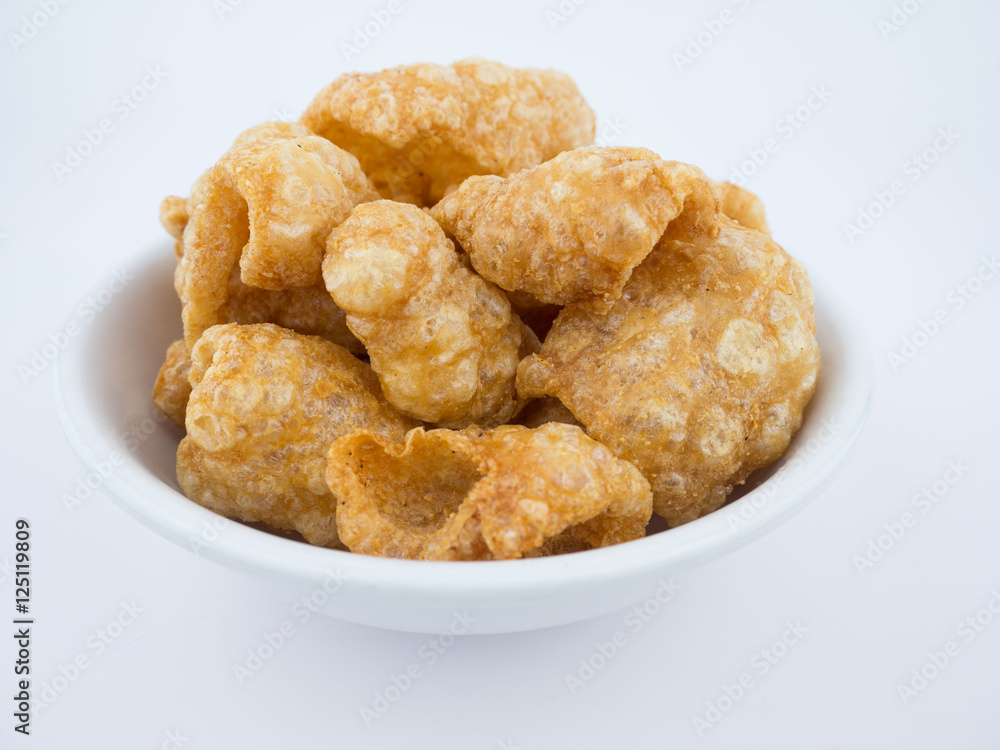 Crispy deep fried pork skin or pork rind in bowl isolated on white background Crispy deep fried pork skin or pork rind in bowl isolated on white background