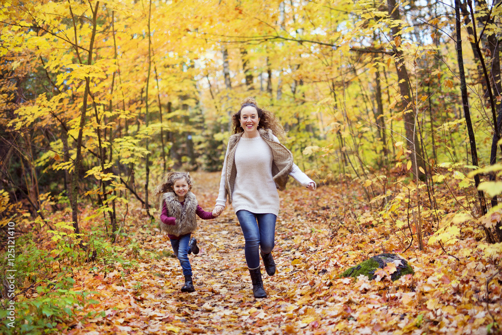 Fototapeta premium Young mother playing with her daughter in autumn park