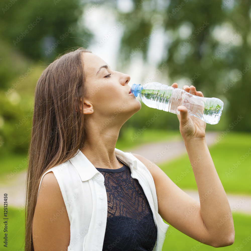 Portrait of young beautiful dark haired woman drinking water Portrait of young beautiful dark haired woman drinking water