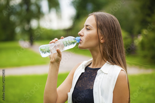 Portrait of young beautiful dark haired woman drinking water