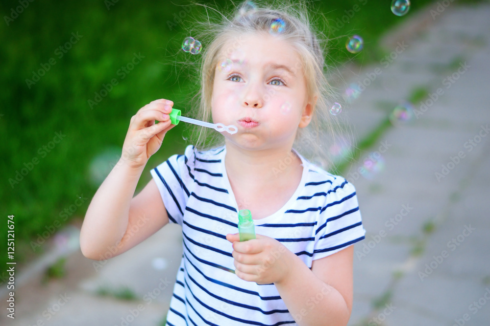 A little adorable girl blowing soap bubbles A little adorable girl blowing soap bubbles
