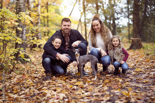 Family of four enjoying golden leaves in autumn park