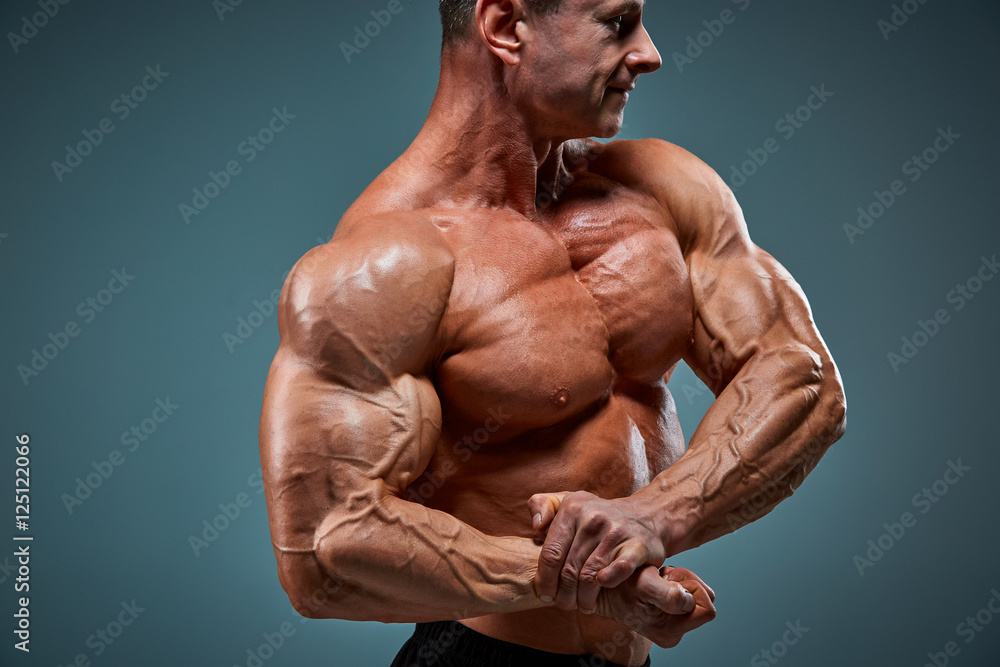 Fototapeta premium torso of attractive male body builder on gray background.