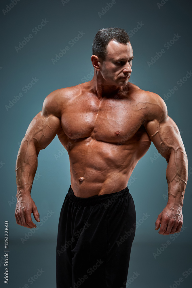 torso of attractive male body builder on gray background. torso of attractive male body builder on gray background.