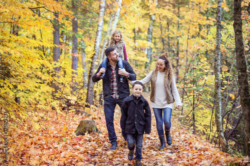 Family of four enjoying golden leaves in autumn park © Louis-Photo
