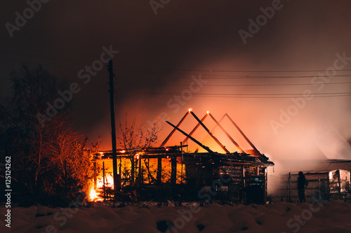 Foto Silhouettes of people near a burning wooden house. long exposure