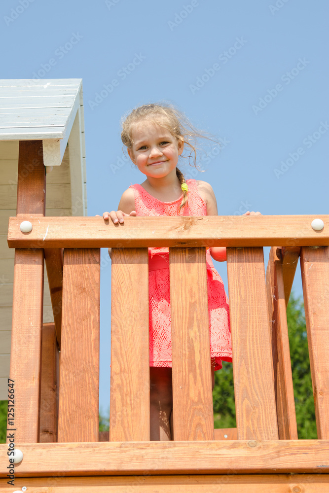 Happy little girl in a pink dress on playground