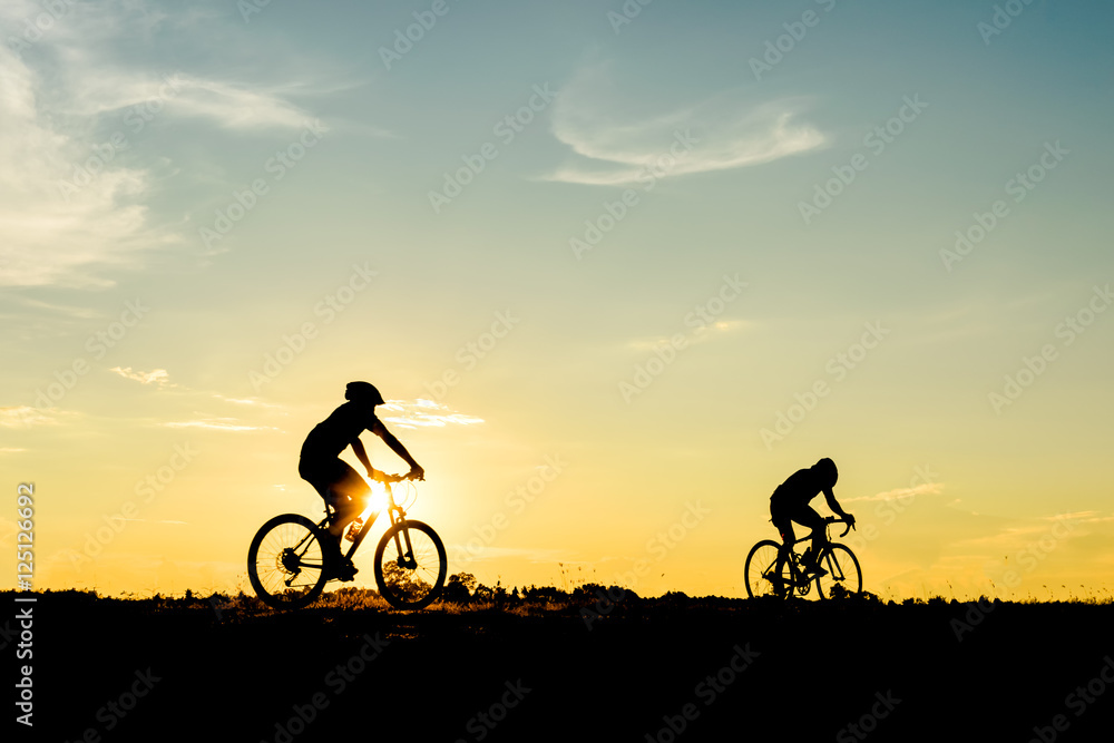 Obraz premium Silhouette of cyclist with friend motion on sunset background