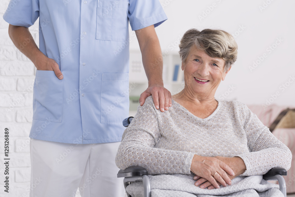 Fototapeta premium Caregiver and woman on wheelchair with a hand on her shoulder