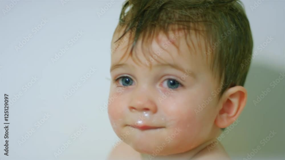 Adorable little boy sits in the bathtub with wet hair and bubbles on his face, smiling big Adorable little boy sits in the bathtub with wet hair and bubbles on his face, smiling big