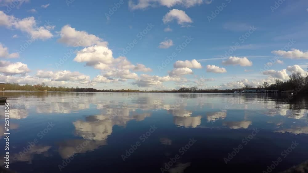 Patches of clouds travelling through the sky and their reflection in a lake, time lapse. Patches of clouds travelling through the sky and their reflection in a lake, time lapse.