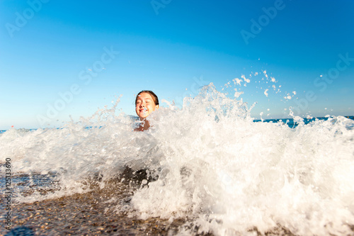 Happy young girl enjoying in sea splashing waves. Mediterranean