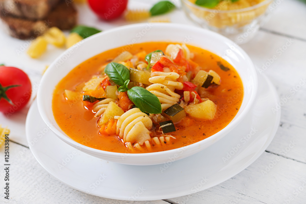 Minestrone, italian vegetable soup with pasta on white wooden table Minestrone, italian vegetable soup with pasta on white wooden table