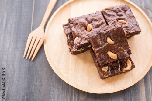 Chocolate brownie with cashew nuts on wooden background.