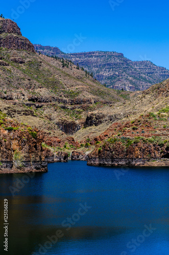 Red mountains, dark water and blue sky