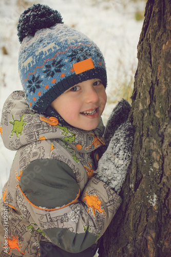 Smiling boy in the winter pine forest