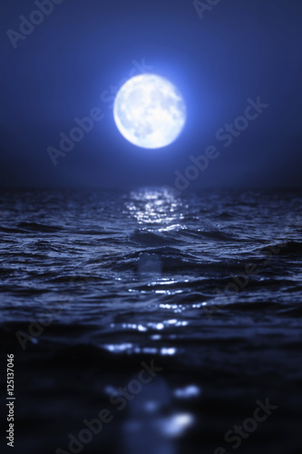 Full moon rising over empty ocean at night