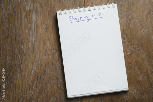 shopping list on notepad on wood table photo