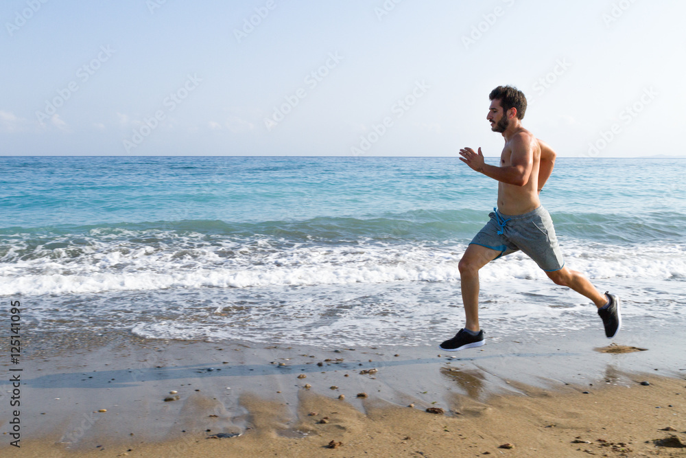 Man runner sprinting on wet sand run at the beach Man runner sprinting on wet sand run at the beach