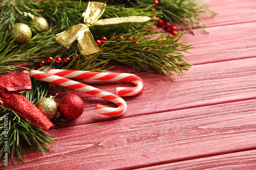 Christmax tree branch with baubles, candies on red wooden table photo