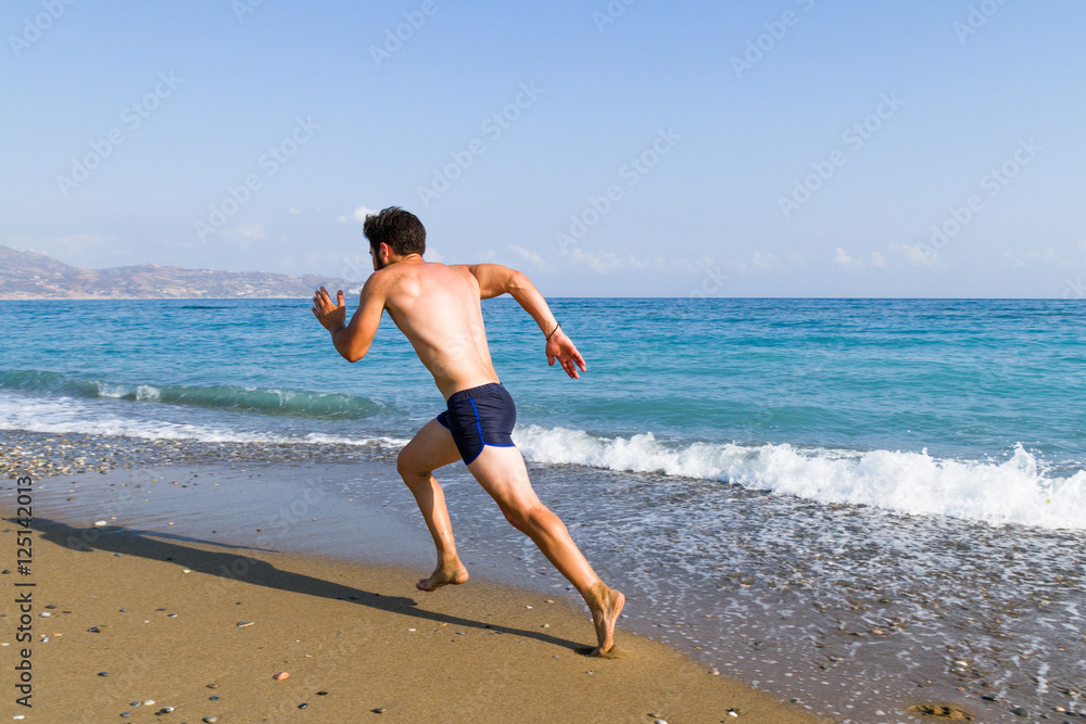 Man runner sprinting on wet sand run at the beach Man runner sprinting on wet sand run at the beach