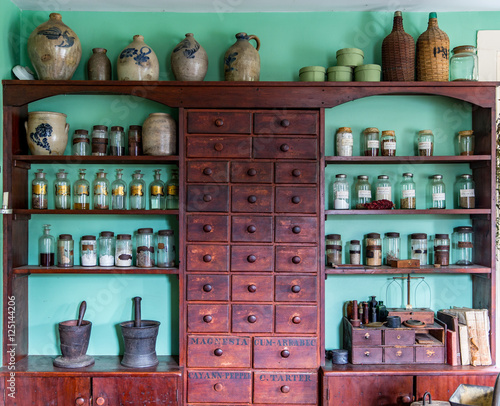 Obraz na plátně Vintage Wooden Apothecary Cabinet with Glass Jars Mortar and Pestle and Crocks