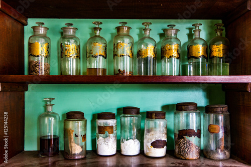 Antique Apothecary Jars in an Brown Cabinet Shelves Turquoise Blue Background