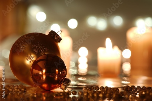 Golden Christmas balls and beads with reflection against candlelight background photo