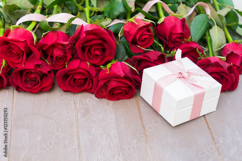Dark Red buds of valentines day roses on wood with gift box