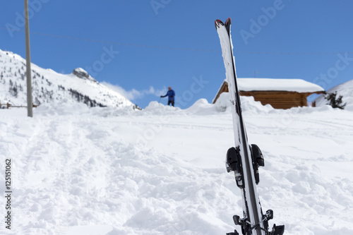 close up of skis in the snow with background blue sky and the ski slope