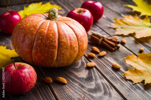 wood background with pumpkin, apples, maple leafes, nut and cinn photo