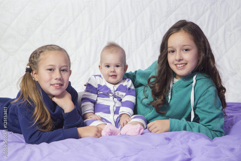 Three sisters, baby and two older sisters playing in the bed. . Three sisters, baby and two older sisters playing in the bed. .