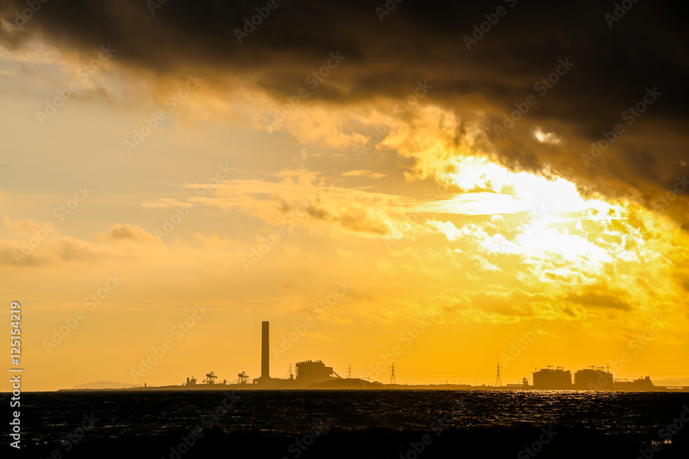 Power plant factory silhouette over sunset at sea Power plant factory silhouette over sunset at sea