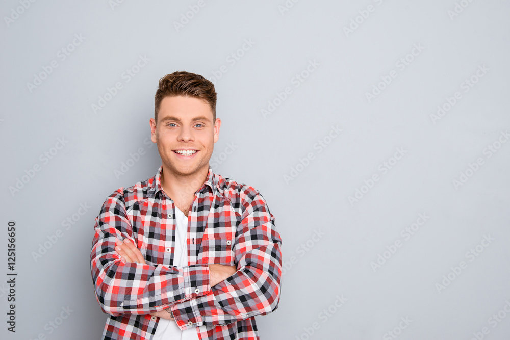 Happy cheerful young guy with crossed hands on gray background Happy cheerful young guy with crossed hands on gray background