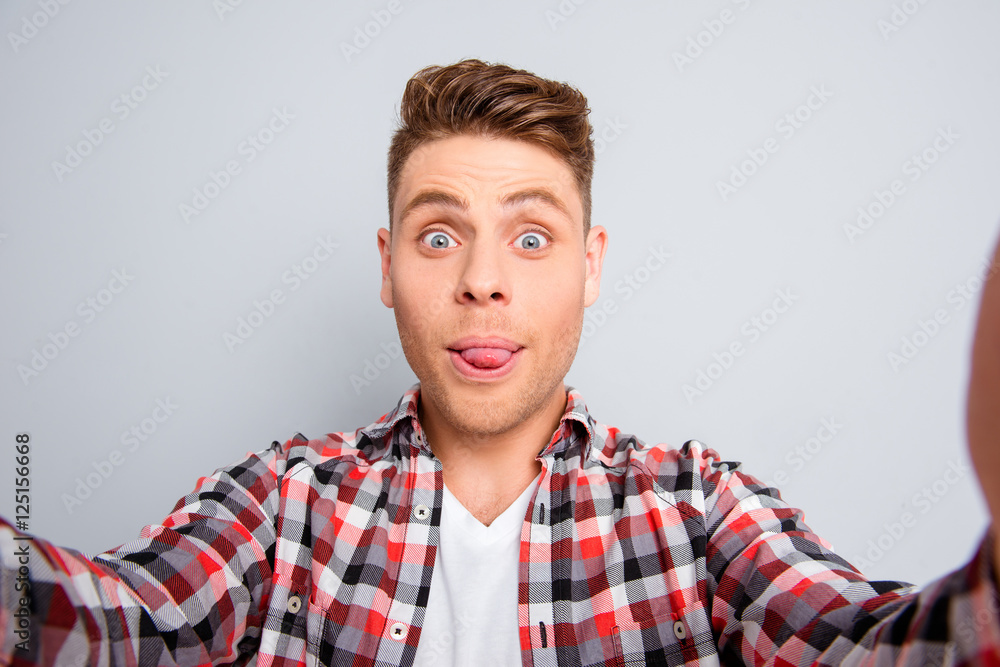 Handsome comic man showing tongue and making selfie Handsome comic man showing tongue and making selfie