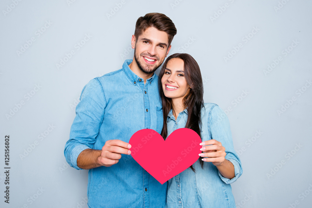 Young happy couple in love holding red paper heart