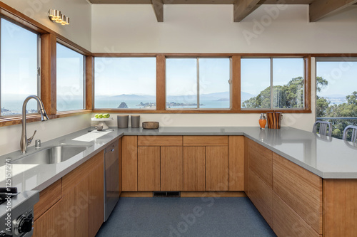 Fototapeta Naklejka Na Ścianę i Meble -  Wooden kitchen in modern home with sea view and stainless steel appliances.