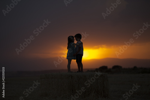 pareja de niños sobre el trigo disfrutando de la puesta de sol