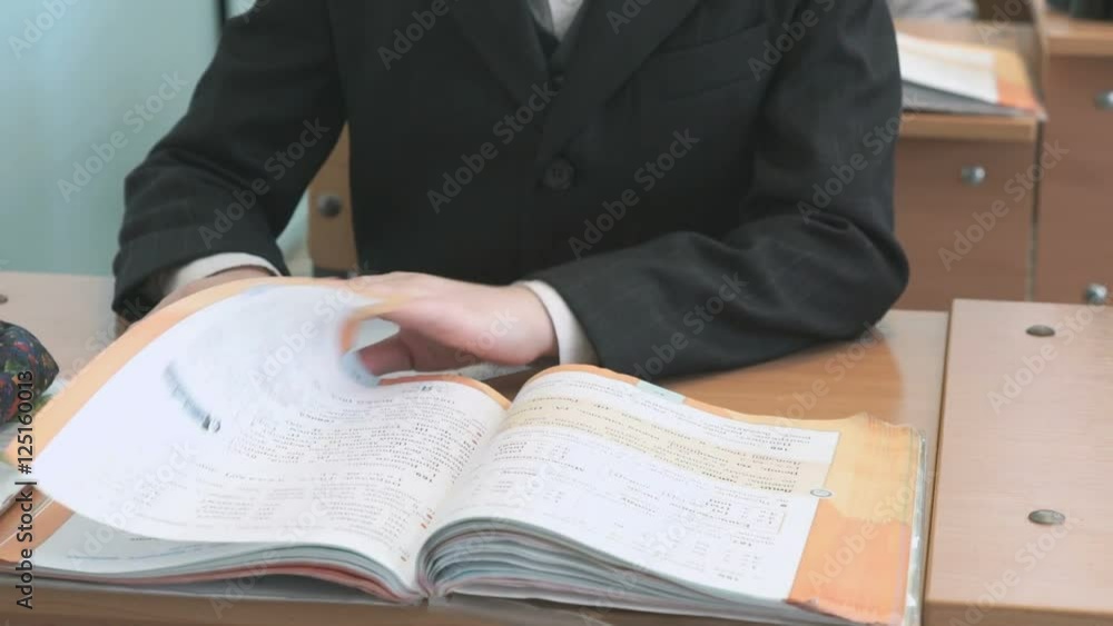 The boy flips the pages of textbook at school The boy flips the pages of textbook at school