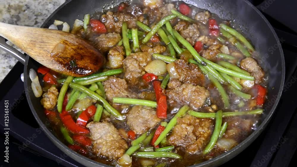 A chef stirs sizzling hot beef stir fry with carrots, beef, beans