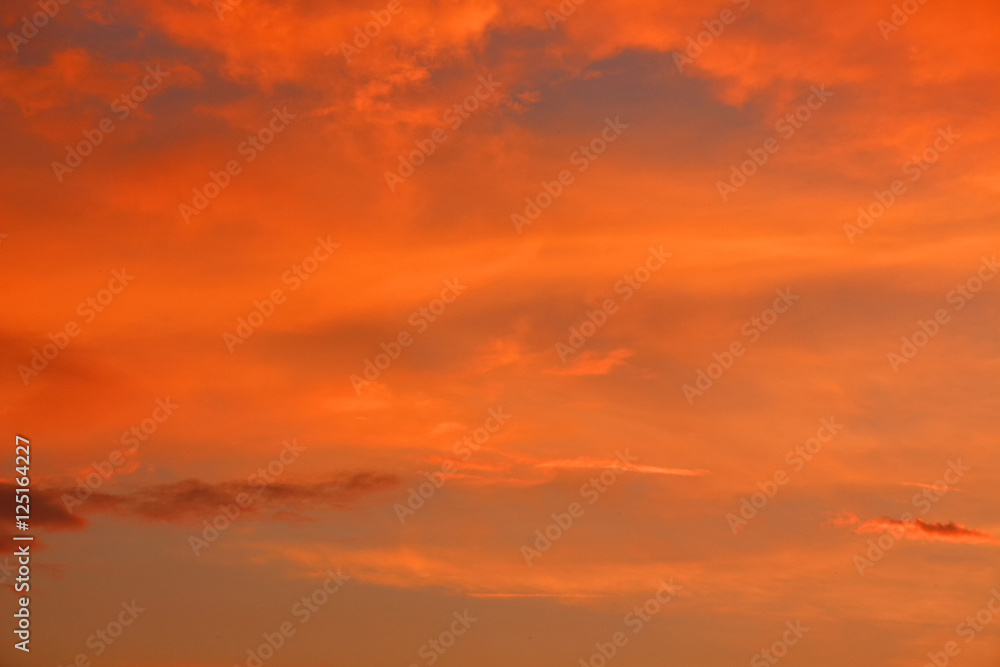 Evening sky at sunset in scarlet colors with orange dense clouds