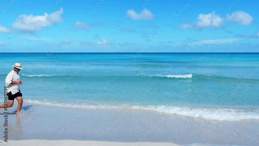 Mature caucasian man running along a tropical beach.Slow motion, high speed camera Mature caucasian man running along a tropical beach.Slow motion, high speed camera