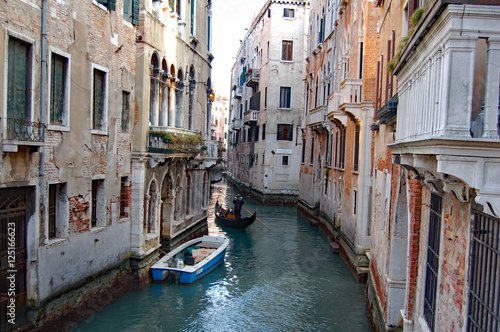 Venice side canal of one moored boat and a gondla in it © Randy Charlston