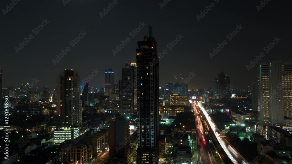 Timelapse shot of night in Bangkok. Moon rising over Thailand capital. Cityscape with illuminated buildings and busy road Timelapse shot of night in Bangkok. Moon rising over Thailand capital. Cityscape with illuminated buildings and busy road