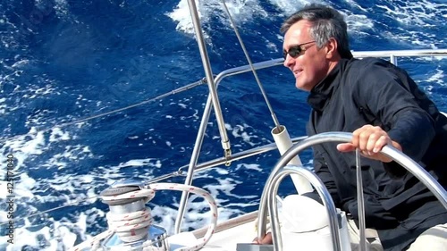 Mature adult skipper driving a sailboat. Slow motion and High speed camera.