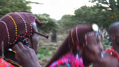 Masai warriors in traditional clothing, play and sing in the twilight after sunset. It is evident due to poor light but the sun is stored absolute authenticity of Masai life.