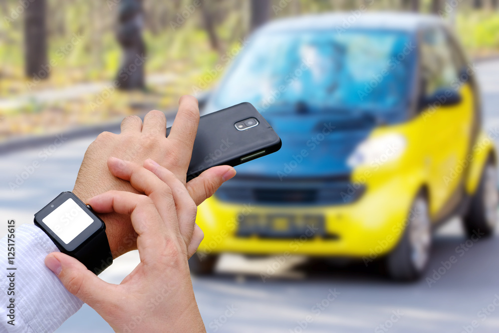 Mans hands with smart watch and mobile phone on yellow car on background Mans hands with smart watch and mobile phone on yellow car on background