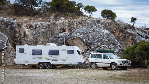 Four wheel drive vehicle and large caravan against a cliff back