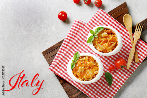 Delicious pasta Al Forno in bowls on napkin. Word ITALY on background. Italian food concept.